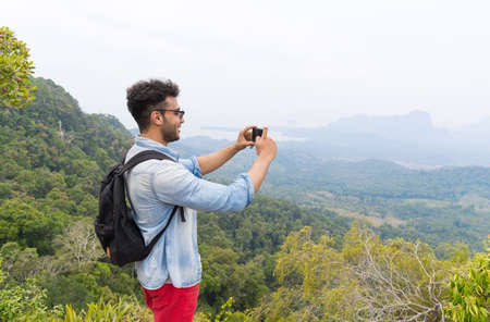 Woman With Backpack Take Photo Of Landscape From Mountain Top On Cell Smart Phone, Young Guy On Hikeの写真素材