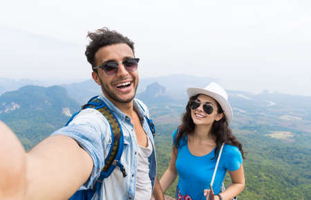 Couple With Backpacks Take Selfie Photo Over Mountain Landscape Trekking, Young Man And Woman On Hike Tourists Adventure Activityの写真素材