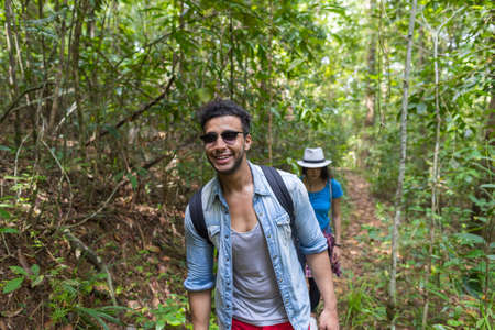 Couple With Backpacks Trekking On Forest Path, Young Man And Woman On Hike Tourists Adventure Activityの写真素材