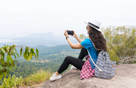 Woman With Backpack Take Photo Of Landscape From Mountain Top On Cell Smart Phone Back Rear View, Young Girl On Hikeの写真素材