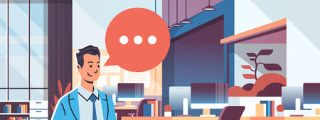 businessman holding tablet speech chat bubble icon over modern workplace cabinet room office...