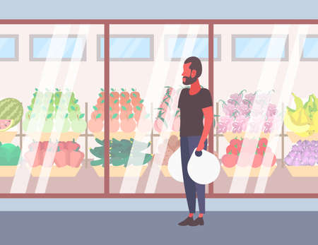 casual man holding shopping bags walking in front of fresh organic fruits vegetables modern supermarket shop glass window guy customer full length cartoon character flat vector illustrationのイラスト素材