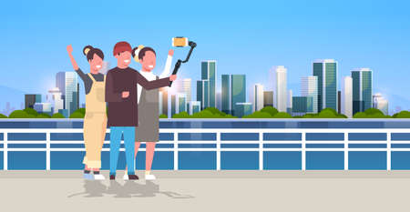 casual people using 3-axis gimbal stabilizer selfie stick for smartphone happy tourists taking photo standing together over cityscape background horizontal full length vector illustrationのイラスト素材