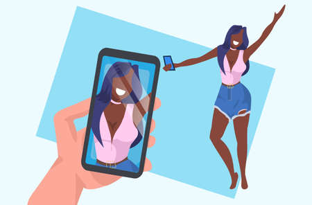 casual woman taking selfie on smartphone camera hand holding cellphone with photo on screen african american female cartoon character posing flat full length horizontal vector illustrationのイラスト素材