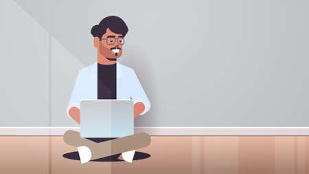 indian man sitting lotus pose using laptop guy working from home freelance concept modern room...