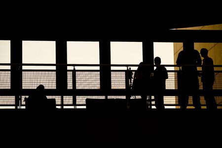 A group of people meeting in a modern building shilouetted against the warm sunset glow.の写真素材