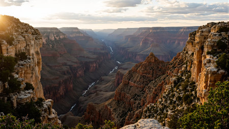 Majestic Grand Canyon at sunset with golden light illuminating its rugged cliffs and deep canyonsの素材