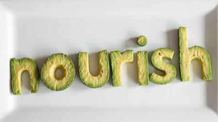 Fresh avocados spell nourish on white plateの素材