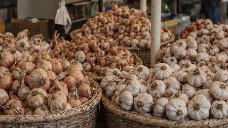 Farmers market stall with fresh onions and garlic bulbs in baskets creating a rustic feelの素材