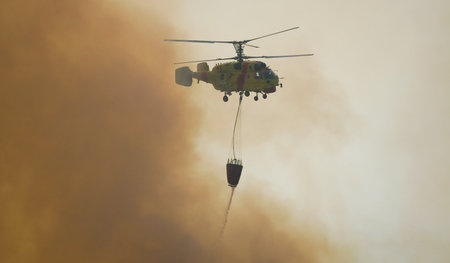 MACEIRA, PORTUGAL - AUGUST 14 : Fire rescue heavy helicopter with water bucket in summer fire in...