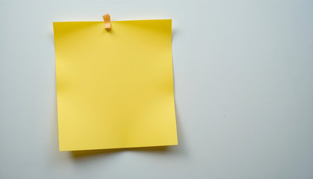 Yellow sticky note on a white background with space for your text.の素材
