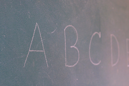 Blackboard with the first letters of the alphabet written on itの写真素材
