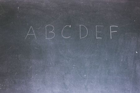Blackboard with the first letters of the alphabet written on itの写真素材