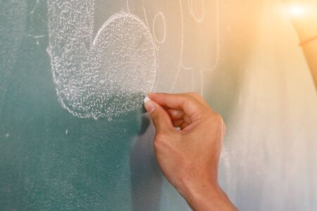 Teacher are teaching student and write a chalk board.の写真素材