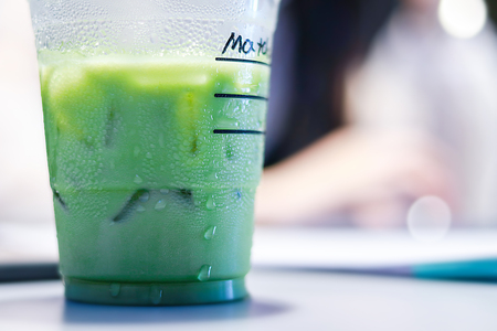 Iced matcha green tea latte on table with women working in store.の写真素材