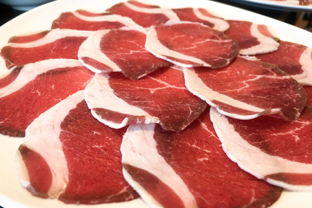 Thin sliced pork meat in black plate prepared for shabu or sukiyakiの写真素材