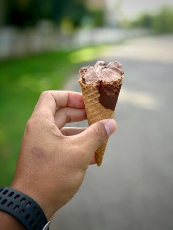 Hand holding ice cream with defocus nature background. Summer season.の写真素材