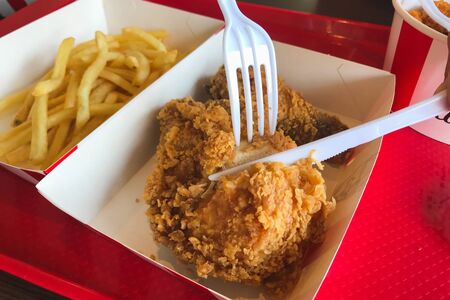 Eating fried chicken with french friesの写真素材