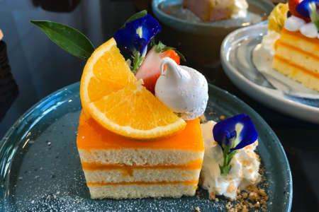 Orange cake with orange topping on plate ready to eatの写真素材
