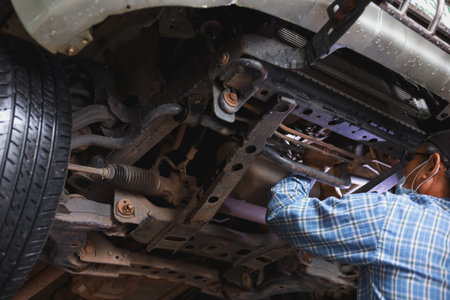 The mechanic is checking the undercarriage of the car.の写真素材