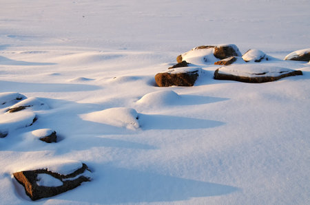 Stones in the snow on a frozen riverの写真素材