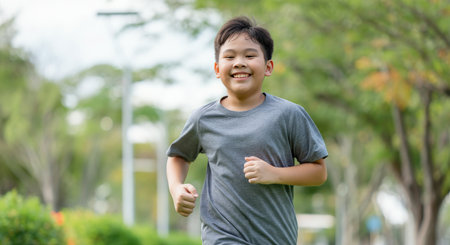Happy asian young boy running outdoors in a park - concept of active lifestyle and joyful childhoodの素材