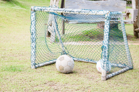Old football, soccer ball  on soccer goalの写真素材