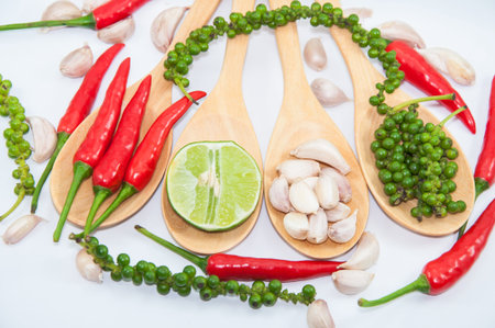 ingredients of thai food on wooden spoon (chili, pepper, garlic and lemon)の写真素材