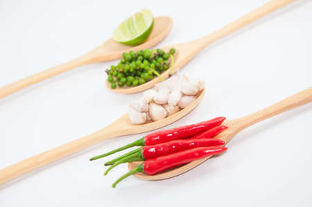 Ingredients of thai food on wooden spoon (chili, pepper, garlic and lemon), focus at chiliの写真素材