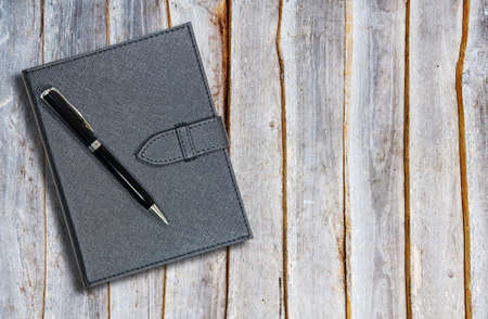 Black leather notebook with pen on the old woodenの写真素材