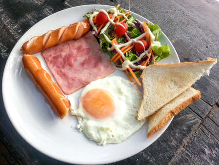 Breakfast foods - fried egg, bacon, sausages breads and vegetable saladの写真素材