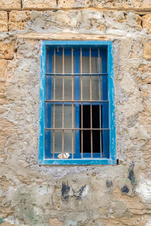 and old blue wooden window behind metal gratingsの写真素材