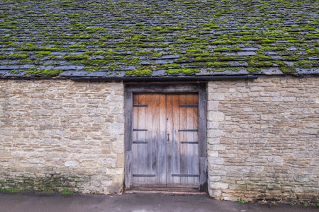 An old village house in England with a wooden door and moss covered roof
