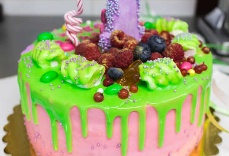 Handmade cake drizzled with a bright glaze and berries, sprinkled with marshmallow, for birthdayの写真素材