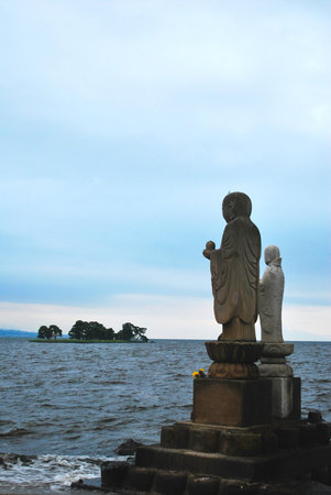 Buddha statues overlooking an island at seaの写真素材