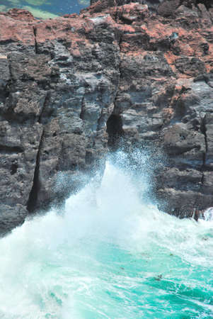 Treacherous waves splashing on cliff rocks, displaying the power of natureの写真素材