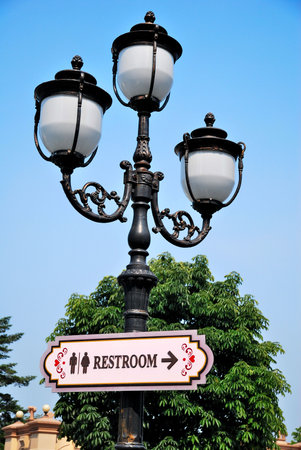 Signage showing direction to restroom with classic looking street lamp 