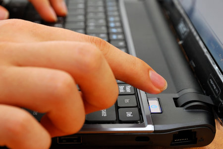 Finger pressing power button on laptop kepboard. For concepts such as electronics and technology,...