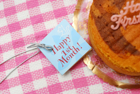 Congratulatory card beside delicious cake for celebrating a baby's first month anniversary. Copyspace available. Suitable for celebration, festivals, and food and beverage concepts.の写真素材