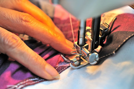 Hand at sewing machine with light on cloth. For concepts such as fashiong and design, work and...