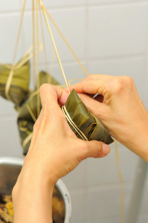 Finishing and tying meat dumplings using rattan strings to prepare for cooking.の写真素材