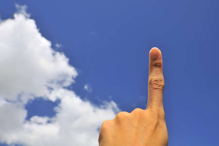 Hand of young male pointing index finger on right of frame with blue sky background.の写真素材