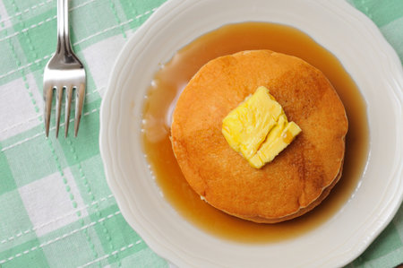 Golden brown pancakes on white plate for healthy breakfast.の写真素材