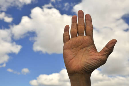 Open palm of an elderly male showing stop sign with blue sky background.の写真素材