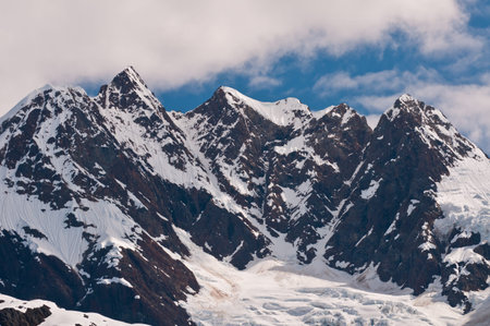 Closeup of towering sharp mountain peaks with glacier ice caps.