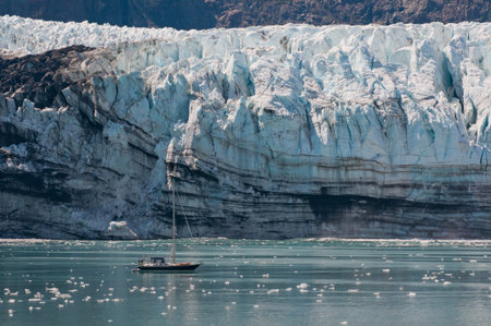 Tiny sailing boat with majestic glacier in background showing contrast.の写真素材