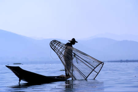 Fisherman in Inle Lake makes a living by using a coop-like trap with net to catch fishのeditorial素材