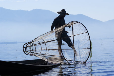 INLE LAKE, MYANMAR - FEBRUARY 17: Fisherman catches fish for food on February 17, 2011 on Inle Lake, Myanmar. Intha people possess the feet-rowing style and the unique fishing equipmentのeditorial素材