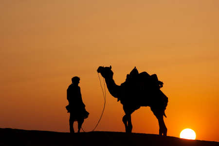 JAISALMER, INDIA - FEB 26  a desert local walks his camel through the Thar Desert, on Feb 26, 2013 in Jaisalmer, India   Apart from farming, camel riding activity is another income source for desert villagers のeditorial素材