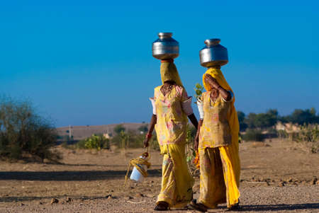 RAJASTHAN, INDIA â FEB 27  women lugging a water pot on their head on February 27, 2013 in Rajasthan, India  Due to the lack of piped water, poor tribals have to fetch water from its natural sources のeditorial素材